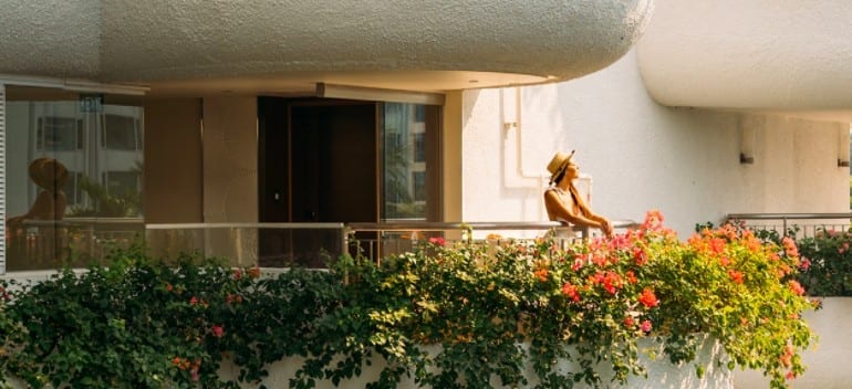 A woman relaxing in the open-air corridors decorated with hanging plants on her luxury staycation