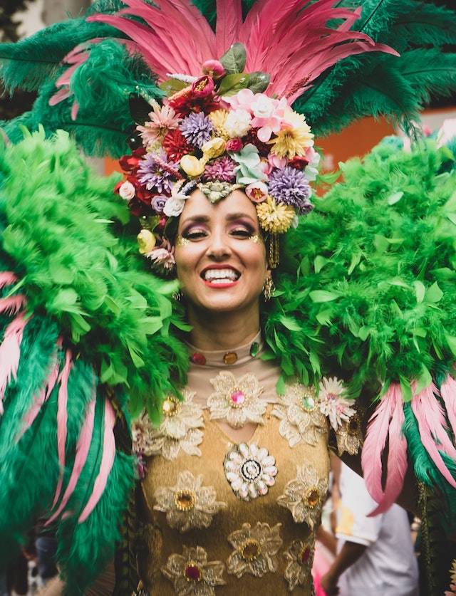 A perfomer dressed extravagantly in green and pink feathers and a brilliant feathery headdress kicks off festivities in Carnaval - a great start to a South American luxury holiday