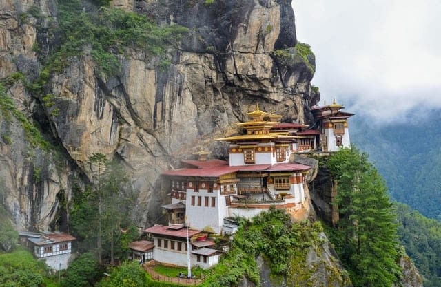 A temple sits serenely on a cliff, astounding visitors on their Bhutan luxury travel.