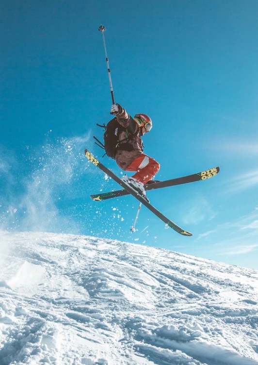 A skiier performing tricks in mid-air down a snowy slope, a treat for everyone in Hokkaido during their Japan luxury travels